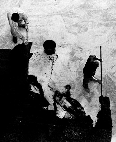 Photographie en noir et blanc : ouvriers étalant du goudron